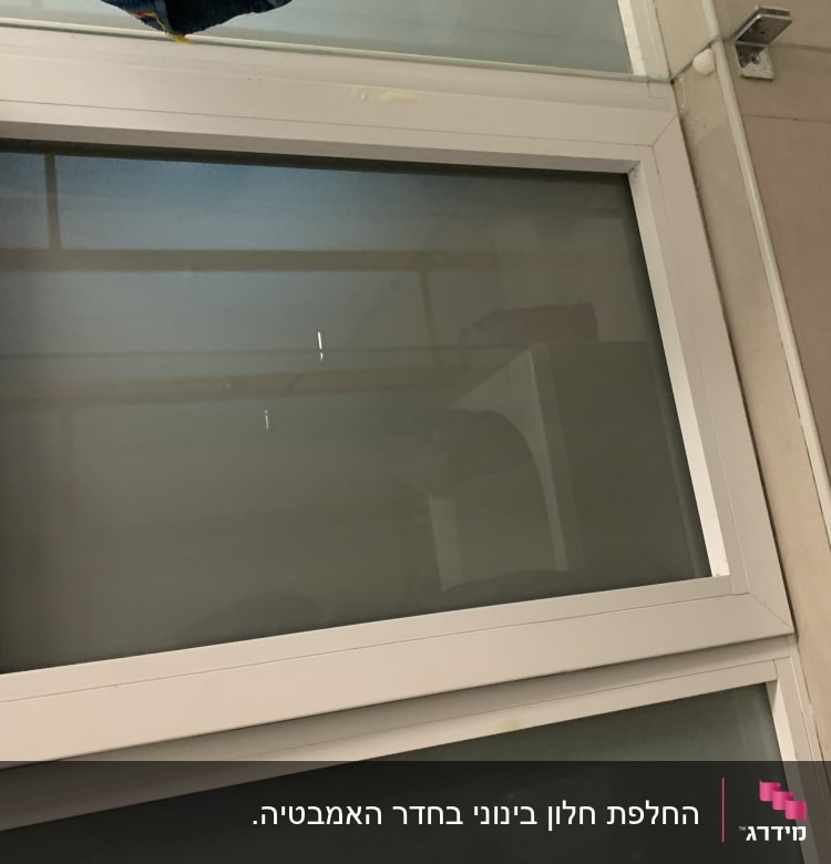 חלון זכוכית עם מסגרת לבנה וקיר בצד